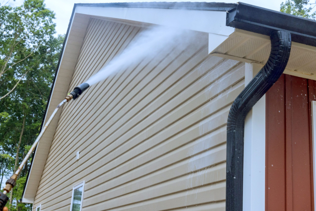 Technician performing soft washing on vinyl siding of a home in Fort Myers.