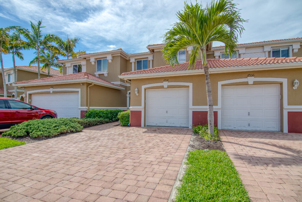 Clean homes and driveways in a sunny Fort Myers neighborhood with tropical landscaping and palm trees.